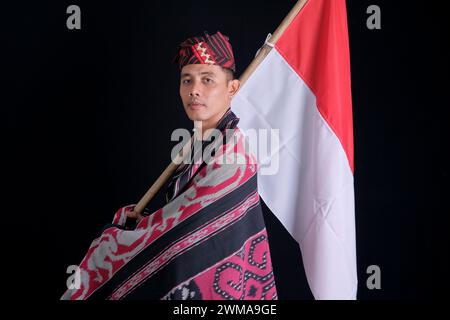 Man wearing traditional woven clothes holding Indonesian national flag in independence isolated on white background Stock Photo