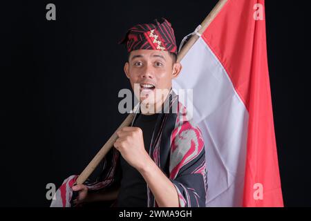Man wearing traditional woven clothes holding Indonesian national flag in independence isolated on white background Stock Photo