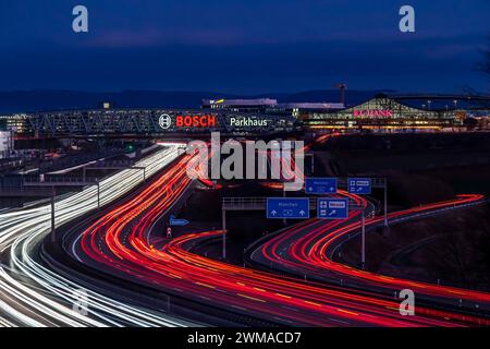 A8 motorway at Stuttgart Airport with Bosch multi-storey car park in the evening, cars create light trails. The 440 metre long construction offers Stock Photo