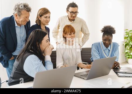 Diverse team evaluating online project - Engaged employees sharing insights - Collaborative digital work analysis. Stock Photo