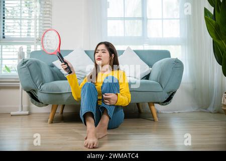 woman sitting floor using mosquito swatter or electric net racket Stock Photo