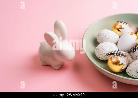 Easter layout with plate of Easter eggs and bunny on pink table. Top view. Stock Photo
