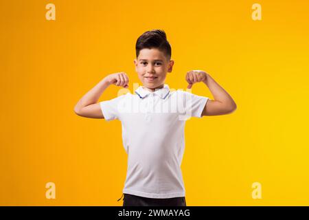Portrait of kid boy showing winner gesture over yellow background. Success and victory concept Stock Photo