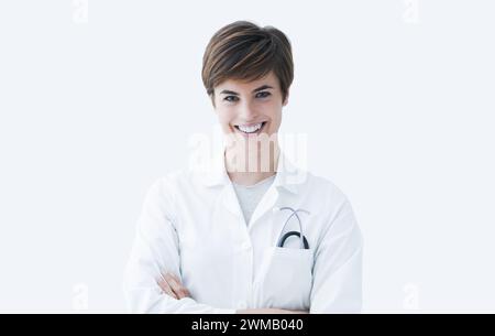 Confident female doctor posing with arms crossed and smiling at camera, healthcare concept Stock Photo