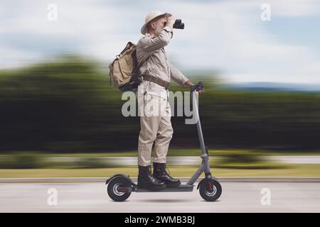 Funny senior explorer riding an e-scooter, sustainable travel and adventure concept Stock Photo