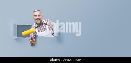 Smiling professional painter posing with roller paint, home repair concept Stock Photo