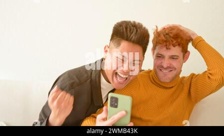 Gay couple looking at mobile phone and celebrating something Stock Photo
