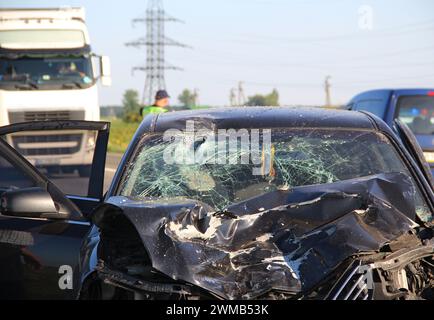 The mangled front part of a car after a head-on crash accident with a truck Stock Photo