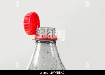 Close up of new cap attached to plastic bottle, isolated on gray background. Environmental protection concept. Stock Photo