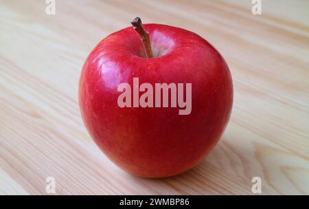 Closeup of a fresh ripe red apple isolated on wooden table Stock Photo