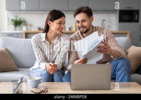 Smiling european spouses reviewing documents in front of laptop Stock Photo