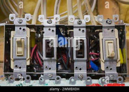 Unfinished wall with exposed yellow fiberglass insulation and electrical switches in residential home. Stock Photo