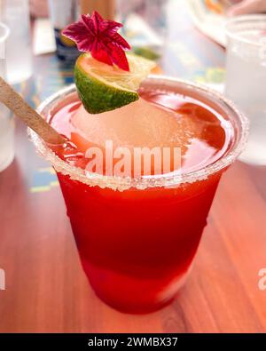 A frosty crimson frozen strawberry daiquiri sitting on table, with its rim salted and a vibrant lime wedge adds a zesty pop of color. Completing the p Stock Photo