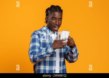 Great App. Amazed young black man looking at smartphone screen with excitement Stock Photo