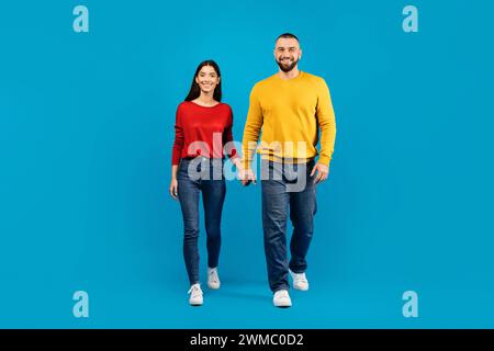 Portrait of happy young caucasian couple holding hands and walking towards camera Stock Photo