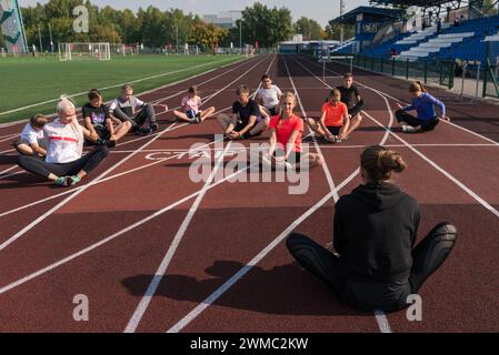 Female coach and group of children conducts a training session at the stadium. School gym trainings or athletics Stock Photo