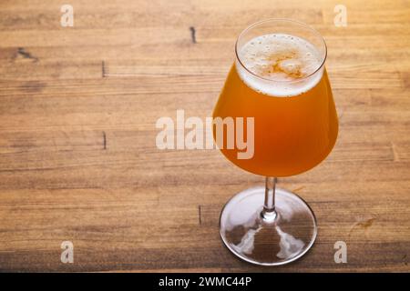 Craft beer in Tulip-shaped stemmed Tiku glass on a rustic wooden table Stock Photo