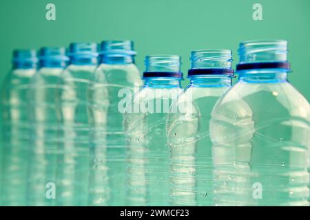 Closeup of open transparent plastic bottles of different shapes and sizes arranged in line against green background Stock Photo