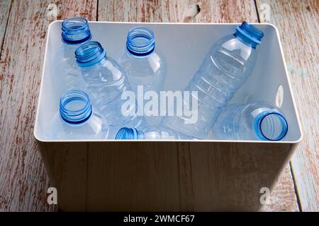 From above of recycled opened empty plastic bottles in a white box placed on a wooden table Stock Photo
