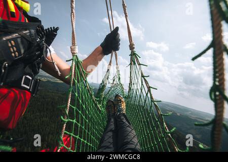 Rescue from difficult to access terrain via helicopter. Pacient in net stretcher with doctor are hanging on rope under helicopter emergency medcical s Stock Photo