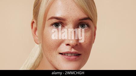 Cropped image of a young female with blond hair and freckled skin. High-detailed portrait of a beautiful young woman with smooth skin. Stock Photo