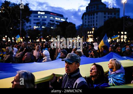 Barcelona, Spain. 24th Feb, 2024. A man wearing a Ukrainian army cap holds a giant ukrainian flag during the anniversary of the second year of war. (Photo by Pol Cartie/SOPA Images/Sipa USA) Credit: Sipa USA/Alamy Live News Stock Photo