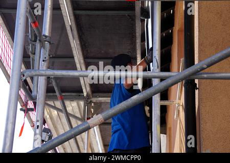 A male worker stands on a scaffold platform while working Stock Photo