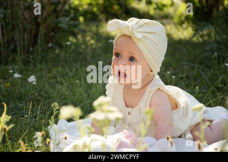 a small child is crying, lying on his stomach on a blanket in the garden on the grass, on a walk, Stock Photo