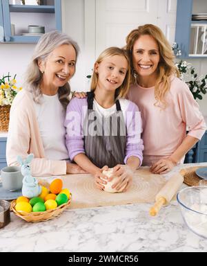 Happy Easter. Portrait of a happy grandmother, daughter and granddaughter in the Easter kitchen while preparing Easter bread and pastries Stock Photo