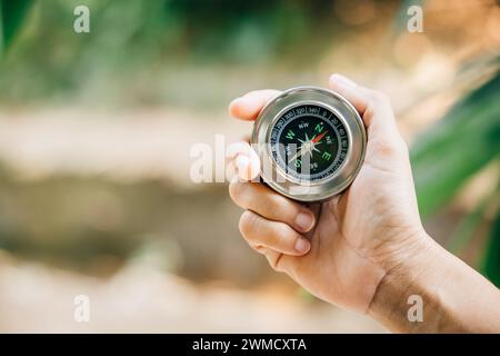 Hiker relies on compass to find direction in forest confusion. compass firmly held by traveler Stock Photo