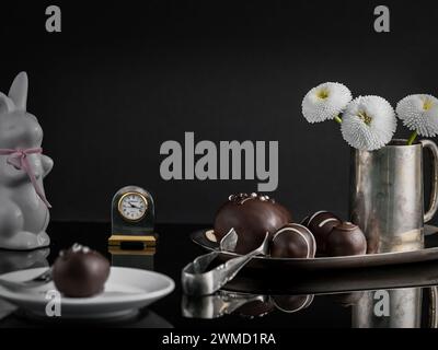 Elegant Easter egg chocolates served on a silver tray, decorated with a silver jug with dewy flowers Stock Photo