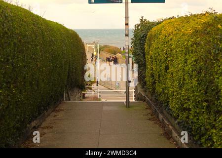 Dublin, Ireland - Februar 24th 2024: A shot of a narrow lane leading to a landscape of people walking along a path in Dun Laoghaire, Dublin. Stock Photo