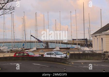 A wide landscape photo of the west pier in Dún Laoghaire during an orange evening sky. Stock Photo