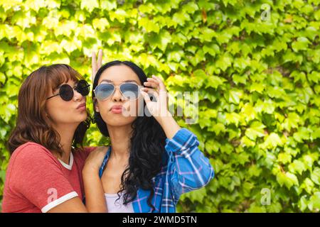 Two young biracial women pose playfully outdoors, with copy space Stock Photo