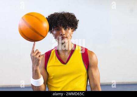 Young biracial man spins a basketball on his finger Stock Photo