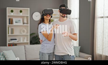 Gorgeous couple sharing love, gaming together with vr glasses at home, exploring futuristic cyber world, smiling and hugging in their cozy living room Stock Photo