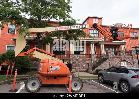 Rental cherry picker boom lift parked in front of a building under renovation. Stock Photo