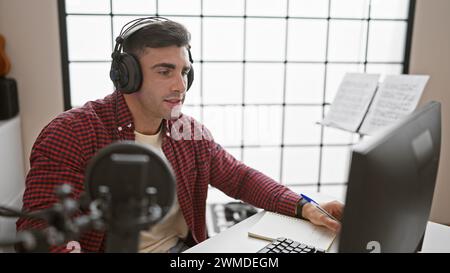 Young, handsome hispanic man, a talented musician, seriously composing a soulful song and singing in an acoustic atmosphere of a music studio, taking Stock Photo