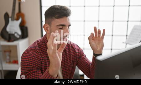 Young, handsome hispanic man, talented musician creating melody in the studio, finding balance and breath through yoga exercise. Stock Photo