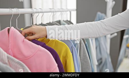 Woman browsing through colorful clothing in a well-organized modern wardrobe indoors. Stock Photo