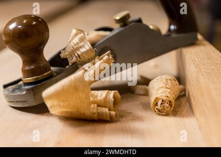 Horizontal photo a detailed shot capturing the intricate curls of wood shavings beside a hand plane on a piece of lumber, highlighting the beauty of c Stock Photo