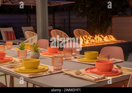 A table set for dinner outdoors at night with a cozy fireplace Stock Photo