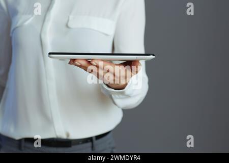 Closeup on middle aged woman employee in white blouse with tablet PC isolated on grey background. Stock Photo