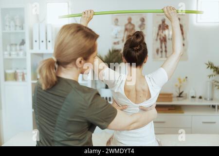 Healthcare time. Seen from behind massage therapist woman in massage cabinet with client conducting examination. Stock Photo