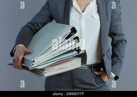 Closeup on business woman in grey suit with folders isolated on grey. Stock Photo