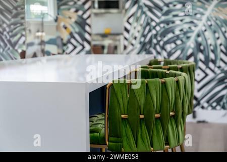 Trendy green velvet and brass barstools at breakfast bar counter in a residential kitchen Stock Photo