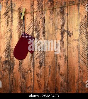 Children's mitten on a rope. Christmas miracle. Waiting for Santa. Christmas background. Wooden planks. Tradition and childhood. New Year. Stock Photo