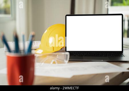 man engineer working on desktop computer with building structures in blueprints laptop white screen mockup for display Stock Photo