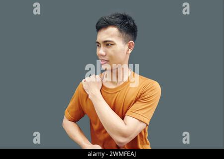 Man massaging stiff shoulders, tired sad man rubbing tense muscles to relieve joint shoulder pain, isolated on blank background. Concept of central ne Stock Photo