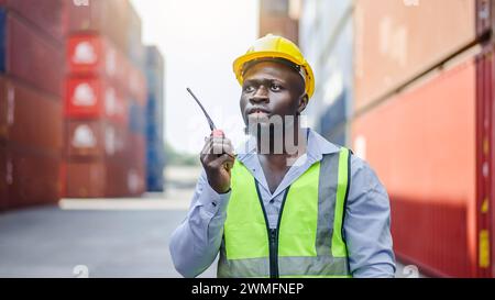 A dock foreman with a radio standing in front of cargo containers Stock Photo